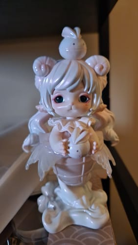 Customer's pearly Mimia Art of Forgotten Dream figure with ram horns standing on a shelf, holding a small bunny.