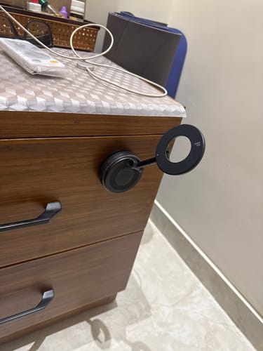 A reviewer's black MagPro Magnetic Phone Holder attached to the side of a wooden drawer, demonstrating its strong grip.