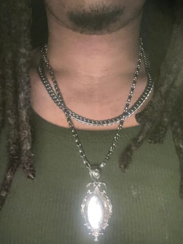 Customer wearing the ornate MIRROR PENDANT on a chain, layered with another necklace.