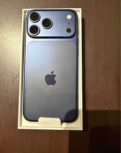 Cliente mostrando un IPHONE 17 PRO MAX azul nuevo en su caja abierta.