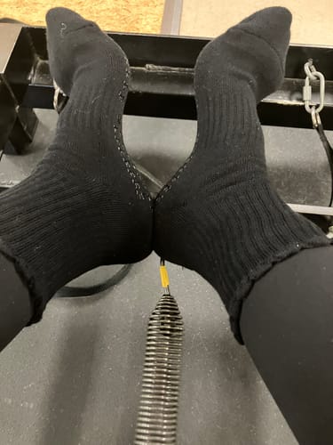 Close-up of a customer wearing black Dual-Direction Grip Basics socks on a Pilates reformer.