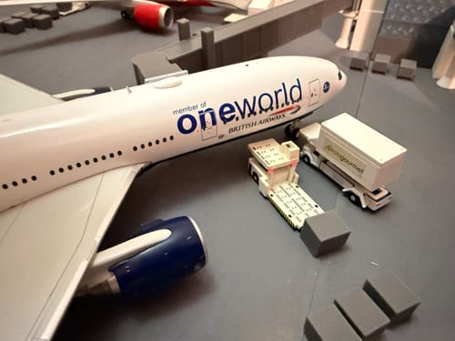 Close-up of a customer's British 777-200ER model at a miniature gate, showing the detailed Oneworld livery.