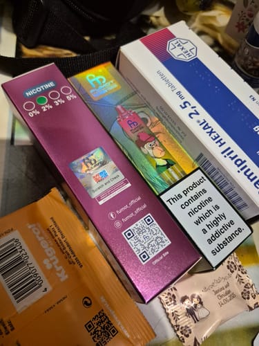 Kunde zeigt die pinke Verpackung des RANDM TORNADO 30000 neben anderen Gegenständen.