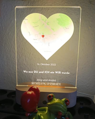 Ein Kunde zeigt das personalisierte Nachtlicht 'Unser Ereignis', das mit einer herzförmigen Karte und Text beleuchtet wird.