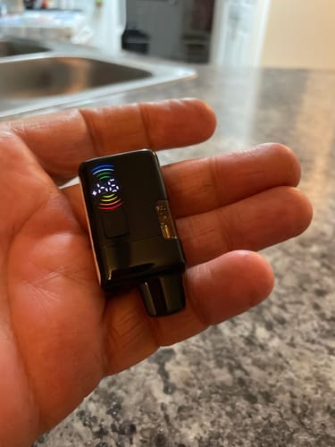 Customer holding a compact, black Flow Vape from the pack, showing its small illuminated screen.