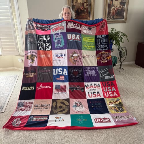 Reviewer holding up their large, colorful Premium T Shirt Quilt in a living room.