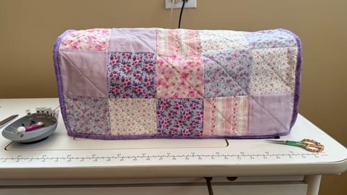 Reviewer's completed patchwork sewing machine cover from the subscription box, shown on a sewing table.