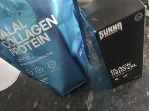 Customer's blue pouch of Halal Collagen Protein on a counter, next to a box of Black Seed Oil.