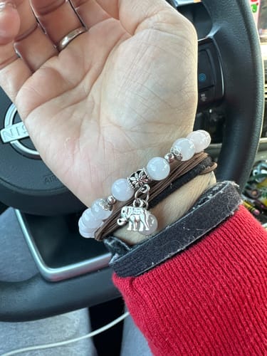 Customer's hand wearing the pink rose quartz bracelet with a small elephant charm.
