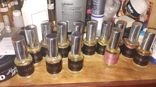 Cliente muestra su colección de perfumes H180 en pequeñas botellas de cristal sobre una superficie de madera.