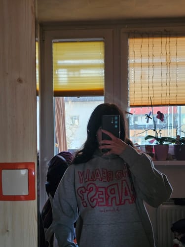 Reviewer taking a mirror selfie in the oversized 'who really cares?' grey hoodie.