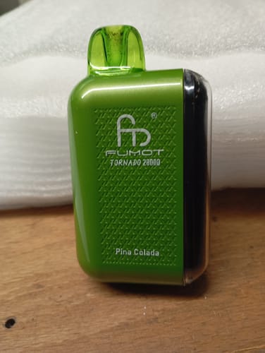 Kunde zeigt seinen grünen RANDM TORNADO 20000 Vape in der Geschmacksrichtung Pina Colada auf einem Tisch.