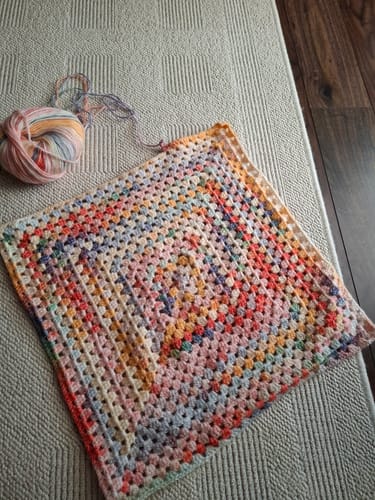A customer's in-progress Hearthside Rainbow Blanket, showing the colorful granny square pattern and the matching yarn.