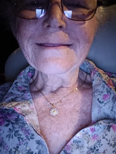 Close-up of a reviewer wearing the You Are My Sunshine Necklace with a sparkling flower pendant.