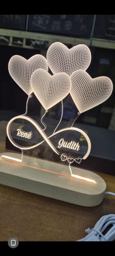 Recensent toont de gepersonaliseerde 3d ballonhartjes Ledlamp, verlicht met de namen 'Rene' en 'Judith'.