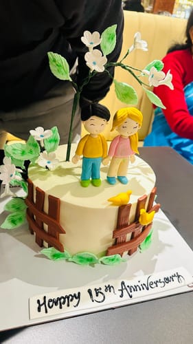 Customer's Romantic Couple Love Cake with fondant figures, flowers, and a 'Happy 15th Anniversary' sign.