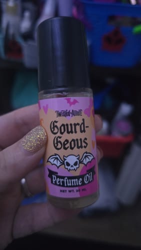 Customer holding the Gourd-Geous Perfume Oil, showing the small bottle and spooky-themed label.