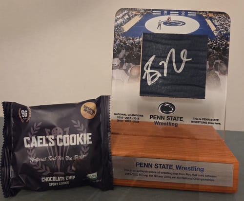 Reviewer's Cael's Cookie in its black packaging, placed beside Penn State Wrestling memorabilia.