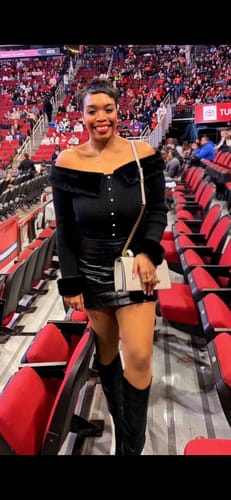 Reviewer at an event wearing sheer seamless tights with a black mini skirt and boots.