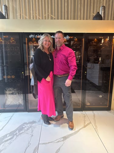 Reviewer standing indoors wearing the pink Everyday Midi Skirt with a black long-sleeve top and black boots.