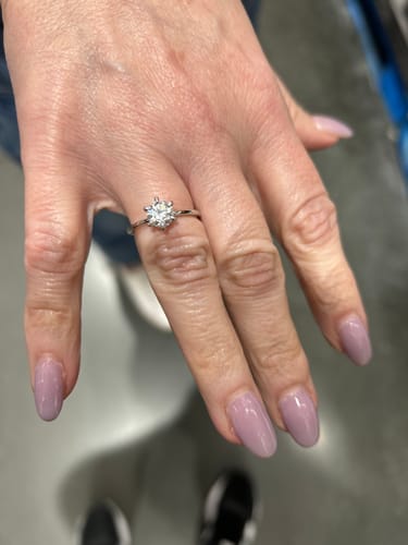 Customer's hand wearing the classic Lucienne ring in a silver finish with its six-prong setting.