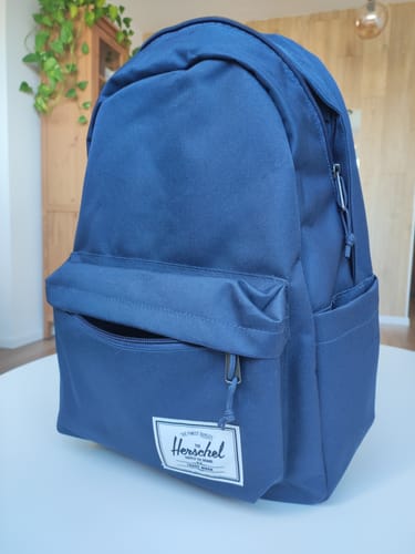 תמונה של לקוח/ה המציג/ה את תיק גב Classic הכחול כשהוא מונח על שולחן.