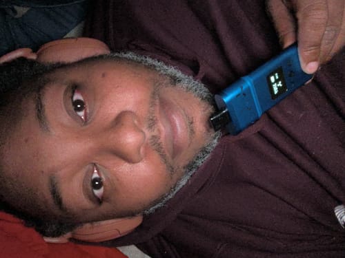 Reviewer holding the blue AirVape X device while lying down.