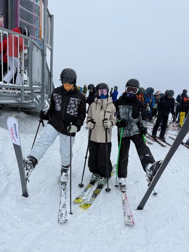 Customer wearing the black baggy snow pants while standing with friends on a ski slope.