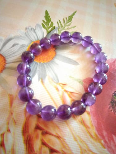 Avis d'un client montrant un bracelet de perles violettes sur une surface fleurie.