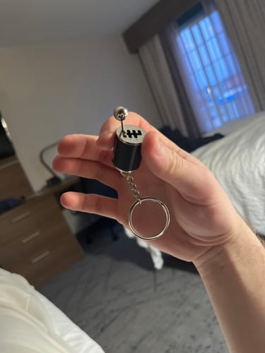 Reviewer holding the black and silver Functional Shifter Keychain in their hand.