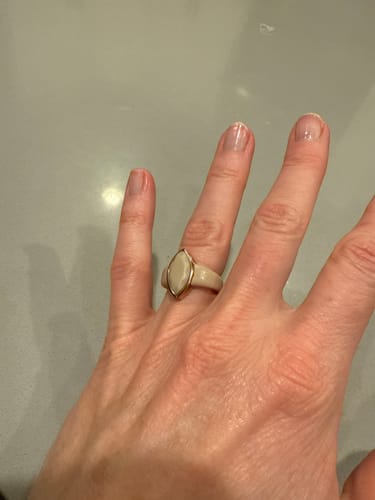 Customer's hand wearing the light-colored Marquise Collection silicone ring with a gold-toned metal frame.