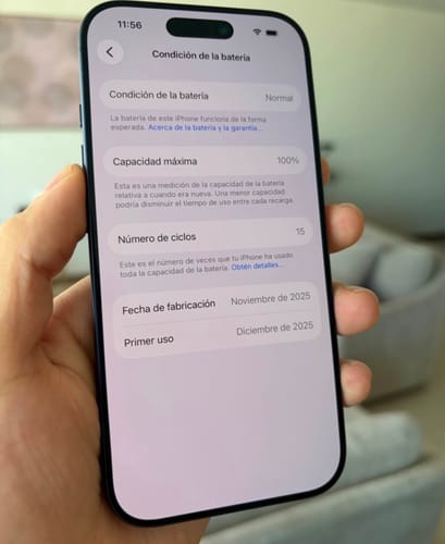 Revisor sosteniendo un iPhone 17 Pro Max azul, mostrando la condición de la batería al 100%.