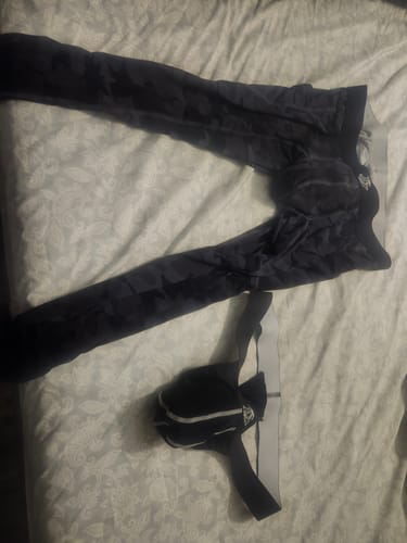 Reviewer's black Nylon Mesh Thong laid out with a pair of dark tights on a bed.