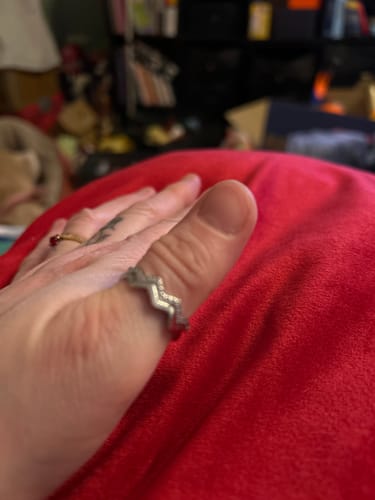 A reviewer's hand showing the zigzag-patterned Highs & Lows Ring on the thumb.
