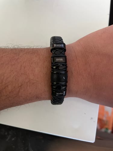 Customer's personalized black bracelet on their wrist, engraved with the names Justice, Ever, and Mars.