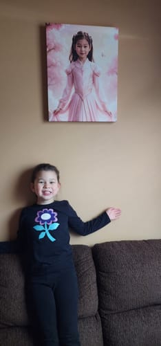 Customer's child smiling in front of their The Mulan’s Blossom Field portrait hanging on a wall.