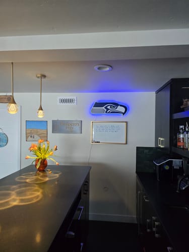 Reviewer's Seattle Seahawks Mascot wall art illuminated with blue LED lights, mounted on a wall over a counter.