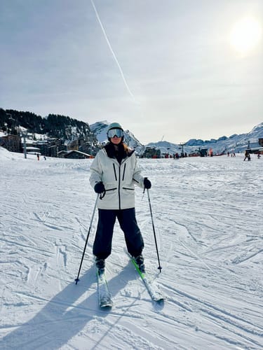 Reviewer standing on skis in baggy, dark Snow Pants on a snowy mountain.