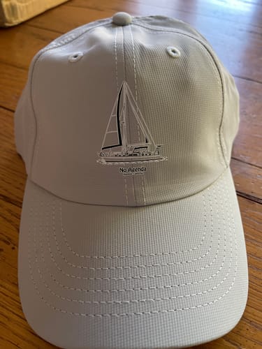 Customer's light grey baseball cap with custom boat artwork of a sailboat and the text 'No Agenda' underneath.