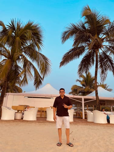 Reviewer standing on a beach wearing the Light Brown Rimless Sunglasses with a golden frame.