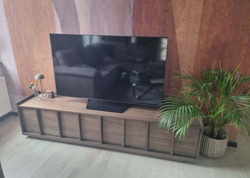 Recensent toont het Onix tv-meubel in een woonkamer, met een 55-inch tv erop en een plant ernaast.