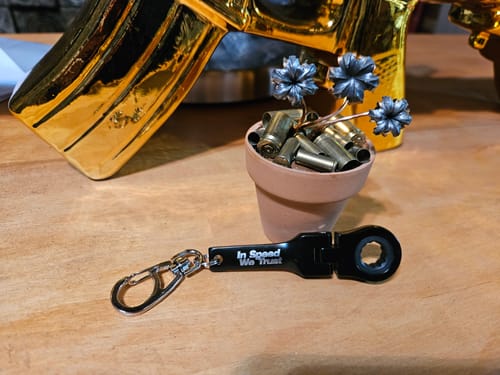 Reviewer's black 10mm Wrench Keychain lying on a wooden table.