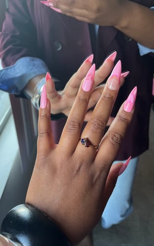 A customer's hand wearing the Leesha Birthstone Ring with two pear-cut stones on a gold band.