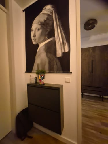 Recensent toont de zwarte by fonQ Klip Schoenenkast die aan een muur in een hal is gemonteerd.