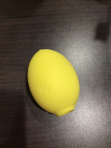 Customer's yellow Lem Clitoral Massager resting on a dark wooden surface.