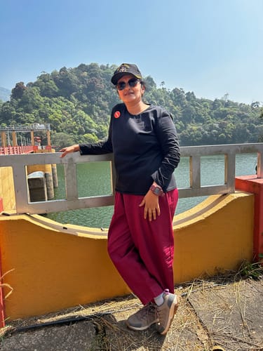 Customer wearing loose, Indian Red Boxate Yoga Pants while standing on a bridge in a scenic, outdoor setting.