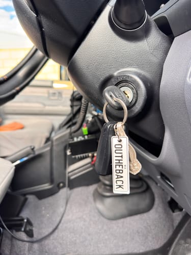 Close-up of a reviewer's white 'Outheback' keyring hanging from their car ignition.