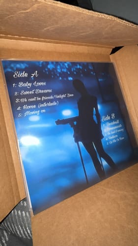 Customer's custom vinyl record showing the blue back cover with a tracklist, still inside the shipping box.