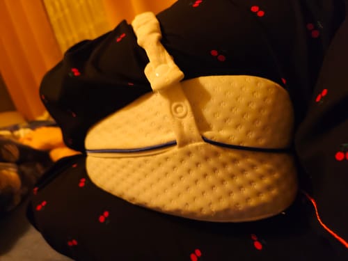 Cliente utilisant le coussin orthopédique pour genoux Cellsius entre ses genoux en étant allongée.
