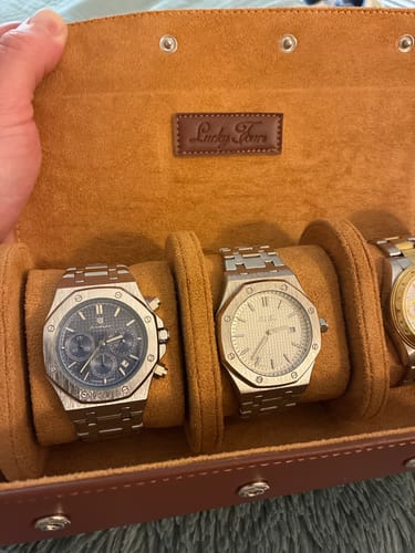 Reviewer holding open a brown Premium Leather Watch Roll with three metal watches secured on the soft interior.
